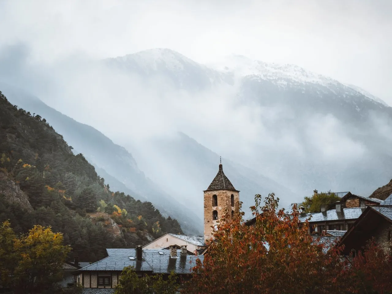 Clocher roman en pierre et montagnes andorranes dans la brume d'automne